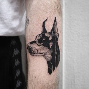 Design featuring a lifelike dog on the forearm, blending blackwork and illustrative styles for a unique and bold look.