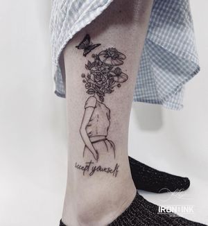 Get a delicate lower leg tattoo in Los Angeles with small lettering and illustrative design of a girl surrounded by butterflies and flowers.