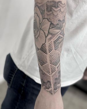 Explore the intricate beauty of Lawrence's blackwork geometric mandala tattoo on your forearm. A mesmerizing fusion of patterns and flowers awaits you.