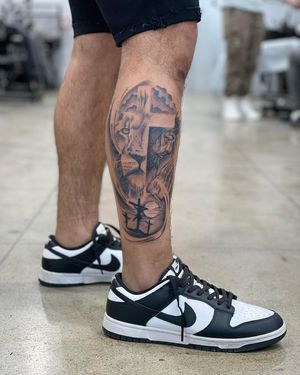 Incredible blackwork realism tattoo of a lion and Jesus on your lower leg, created by Lawrence. Powerful and inspiring design.