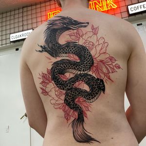Experience the power of the mighty dragon intertwined with the delicate beauty of the peony, expertly inked by Sofia in stunning blackwork style.