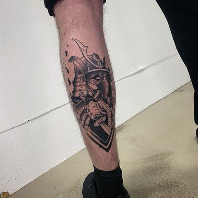 Embrace the strength and honor of the samurai with this blackwork tattoo design featuring a sword, helmet, and mask on your lower leg. Expertly done by tattoo artist Sofia.