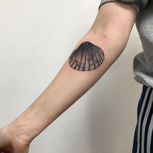 Capture the beauty of the sea with this intricate blackwork shell tattoo on your forearm, designed by Sofia.