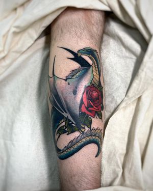 Vibrant neo-traditional forearm tattoo by Sofia featuring a fierce dragon intertwined with delicate flowers.