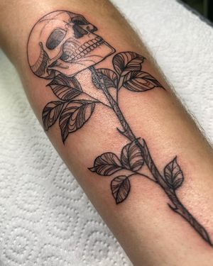 Get a striking blackwork tattoo on your forearm featuring a skull entwined with a leaf, beautifully illustrated by Sofia.