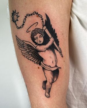 Sofia's blackwork upper arm tattoo features a detailed angel holding a chain with a mace attached, creating a unique and bold design.