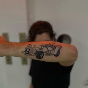 Get behind the wheel of style with Sofia's blackwork illustration of a car on your forearm. Stand out with this unique design.