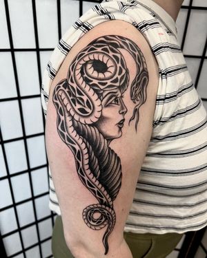 Capture the allure of the snake and beauty of a woman in this blackwork upper arm tattoo by Andre Bertoncin.