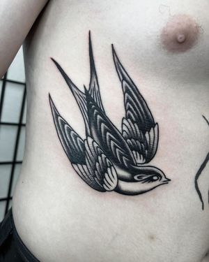 Get inked with a classic blackwork bird design on your ribs by tattoo artist Andre Bertoncin.