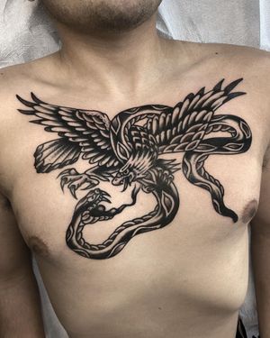 Impressive blackwork chest tattoo featuring a snake and eagle, beautifully illustrated by tattoo artist Andre Bertoncin.
