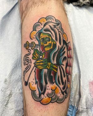 Illustrative traditional tattoo featuring a skull smoking a pipe, done by Shawn Nutting on the lower leg.