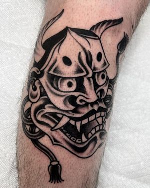 Illustrative blackwork tattoo of a hannya mask by artist Andre Bertoncin on the arm.