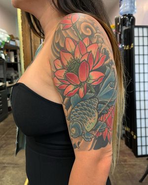 Elegant upper arm tattoo by Daniel Werder featuring a beautiful combination of waves, fish, and peony flower in Japanese neo-traditional style.