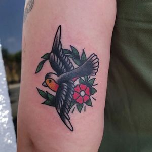 Traditional upper arm tattoo by Arlene Salinas featuring a beautiful bird and flower motif.