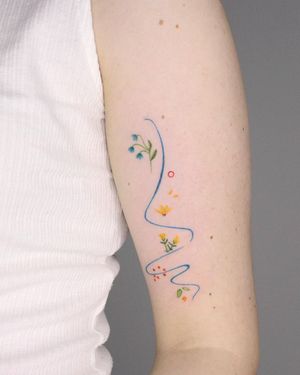 Fine line and illustrative tattoo featuring a sun, flower, and pattern by Tuğçe özbıyık. Perfect for the upper arm placement.