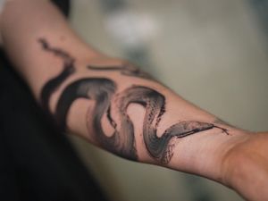 Get a mesmerizing blackwork snake tattoo on your forearm by the talented artists at La Bottega dell'Arte. Stand out with this unique illustrative piece.