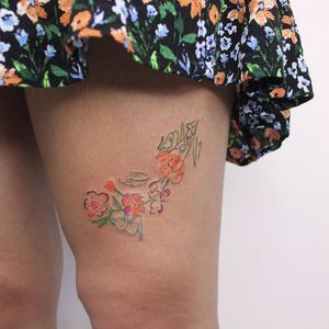 Exquisite upper leg tattoo by Tuğçe özbıyık featuring a delicate flower and elegant woman design.