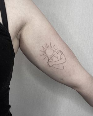 Illustrative upper arm tattoo featuring a radiant sun with a unique pattern, surrounded by a mystical woman. By Dominika Gajewska.