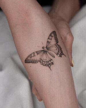 Adrian Mokijewski's blackwork butterfly design on forearm combines beauty with boldness. Stand out with this unique tattoo!