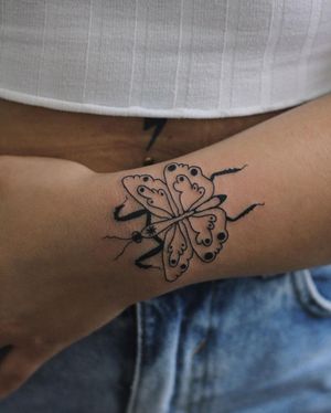 Experience the delicate beauty of a blackwork and illustrative butterfly tattoo on your forearm by the talented artist Kaśka.