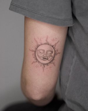 Adrian Mokijewski creates a striking black and gray illustrative design on the upper arm featuring a sun and moon motif.