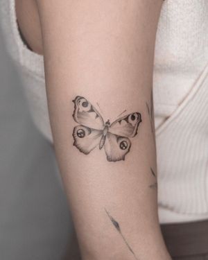 Express your beauty with this blackwork butterfly tattoo for upper arm by renowned artist Adrian Mokijewski.