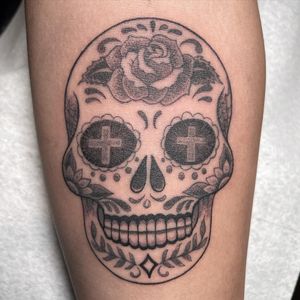 Get an edgy blackwork tattoo featuring a flower, skull, and cross on your arm in Chicago, US.