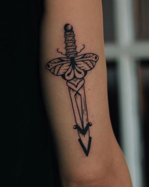 Elegant blackwork design by artist Kaśka, adorning the upper arm with a butterfly and dagger motif.