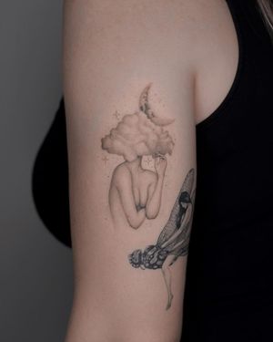 Adrian Mokijewski creates a stunning black and gray illustrative tattoo of a woman with the moon and clouds on the upper arm.