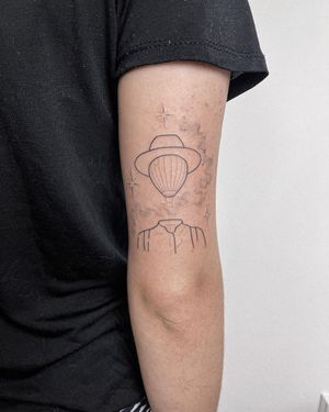 Illustrative upper arm tattoo by Dominika Gajewska featuring a hat and hot air balloon design. Stunning fine line work.