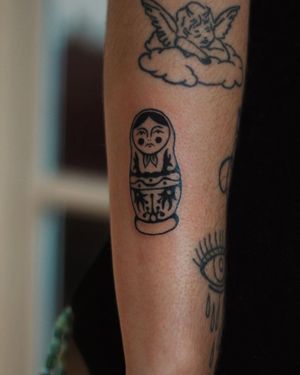 Embrace the intricacy of Russian culture with this illustrative blackwork tattoo of a matrioshka doll on your upper arm.