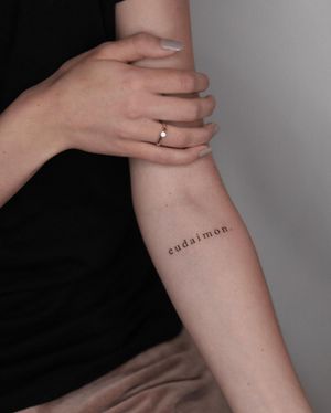 Get a beautiful and delicate forearm tattoo featuring your name and a meaningful quote done by talented artist Adrian Mokijewski.