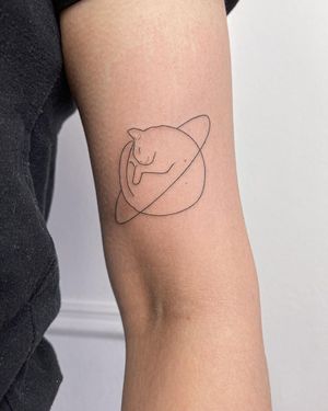Let Dominika Gajewska create a stunning fine line illustrative tattoo of a planet and cat on your upper arm. A unique and whimsical design!