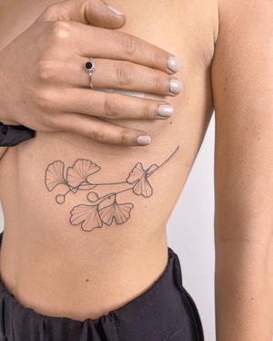 Beautiful illustrative flower tattoo on ribs by Dominika Gajewska. Fine lines and intricate details.
