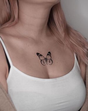 A stunning blackwork and fine line illustrative butterfly tattoo on the chest by the talented artist Adrian Mokijewski.