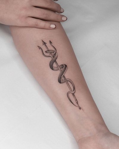 An intricate black and gray forearm tattoo featuring a snake and trident, beautifully rendered by artist Adrian Mokijewski.