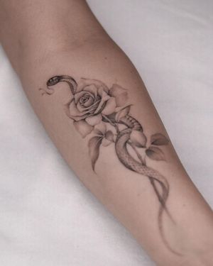 Unique blackwork tattoo by Adrian Mokijewski featuring a snake and flower design on the forearm.