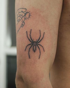 Get tangled in the intricate web of Kaśka's bold blackwork spider design on your upper arm. Stand out with this unique tattoo!