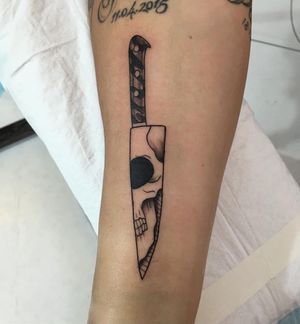 Blackwork illustrative tattoo of a skull and knife done by Natalie Lucia on the forearm.