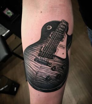 Sean Ross Fawkes' blackwork realism tattoo of a guitar beautifully illustrated on the forearm.