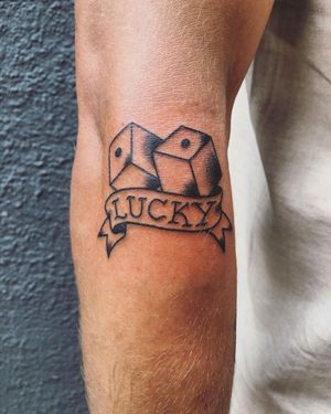 Unique blackwork design by Phil Botha featuring dice and inspiring lettering on upper arm.