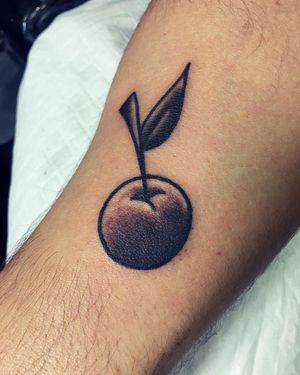 A bold and illustrative blackwork cherry tattoo on the forearm, expertly crafted by artist Phil Botha.
