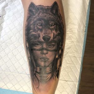 Admire the intricate details of this black and gray realism tattoo on the forearm, featuring a mystical Native woman with a wolf and necklace by artist Sean Ross Fawkes.