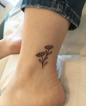 Elegant and detailed flower design on the ankle, artfully created by tattoo artist Natalie Lucia in a fine line illustrative style.