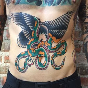Illustrative traditional style tattoo featuring a snake and eagle design, expertly done by artist Phil Botha on the stomach area.