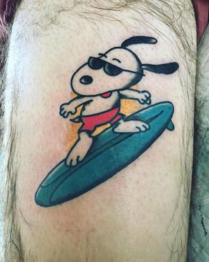 Get a groovy illustrative tattoo of Snoopy catching waves with sunglasses, done by the talented artist Phil Botha.
