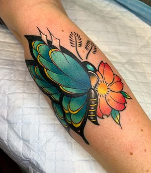 Vibrant neo-traditional piece by Nikita Jade Morgan featuring a beautifully detailed butterfly and flower design on the lower leg.