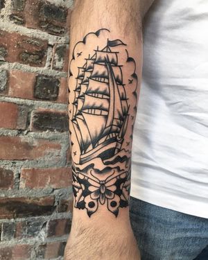 This stunning blackwork tattoo by artist Phil Botha combines a beautiful butterfly and a majestic ship, creating a unique and eye-catching piece.