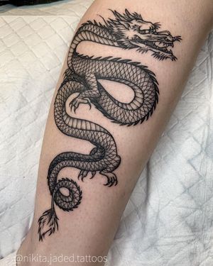 Get inked with a fierce blackwork dragon design by Nikita Jade Morgan on your lower leg for a bold and edgy look.
