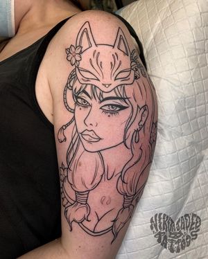 Unique blackwork tattoo featuring a beautiful woman wearing a mask surrounded by cherry blossoms, done by Nikita Jade Morgan on the upper arm.